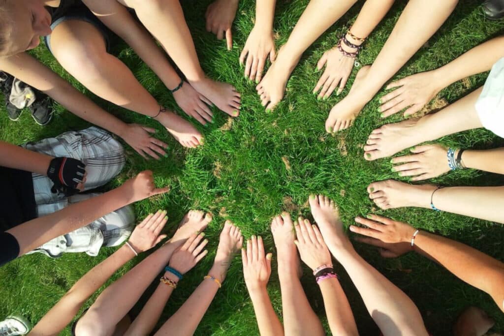 Team members placing hands and feet in a circle on a lawn
